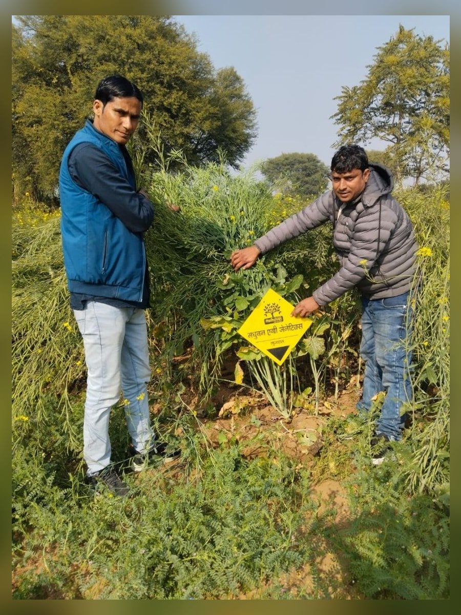 Field partners with a Madhuvan Agri Genetics yellow brand sign